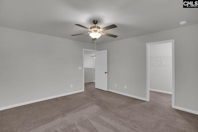 unfurnished bedroom with a spacious closet, a closet, ceiling fan, and carpet flooring