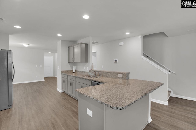 kitchen featuring gray cabinetry, sink, stainless steel refrigerator, and kitchen peninsula