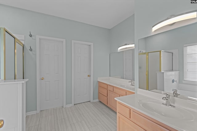 full bath featuring a stall shower, baseboards, two vanities, and a sink