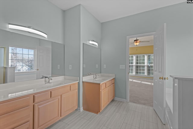 full bathroom with a ceiling fan, two vanities, a sink, and baseboards