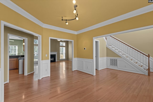 interior space featuring a fireplace, visible vents, stairway, light wood-style floors, and ornamental molding