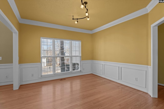 spare room with visible vents, crown molding, a textured ceiling, light wood-type flooring, and track lighting