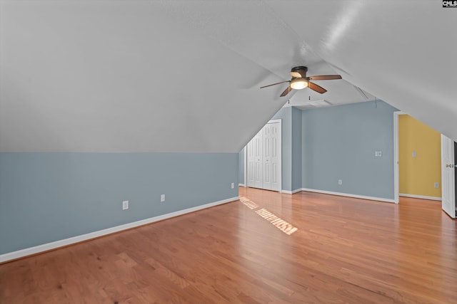 additional living space with lofted ceiling, wood finished floors, a ceiling fan, and baseboards