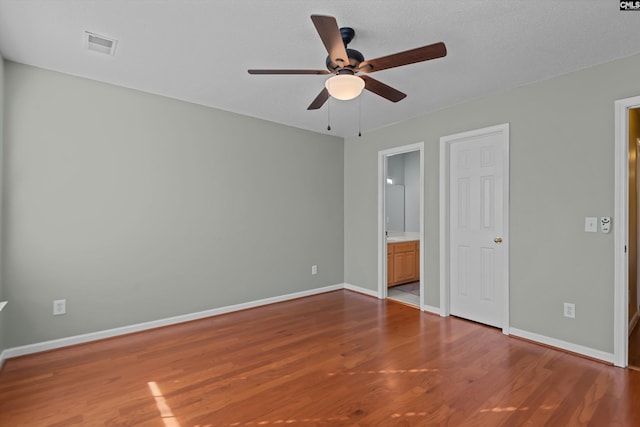 unfurnished bedroom featuring wood-type flooring, ensuite bathroom, and ceiling fan