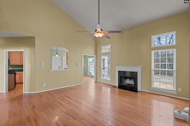 unfurnished living room with light hardwood / wood-style flooring, high vaulted ceiling, and ceiling fan