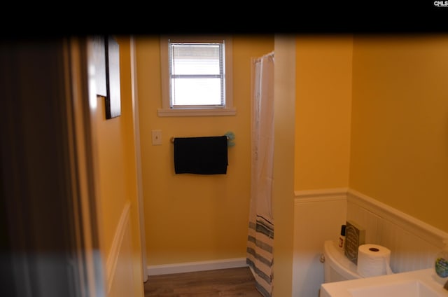 bathroom with wood-type flooring, toilet, and a shower with shower curtain