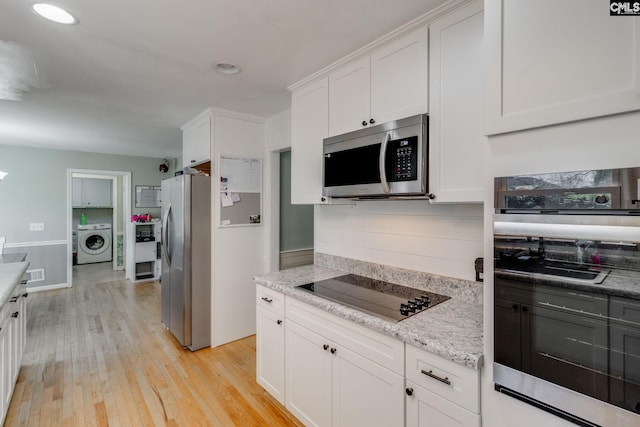 kitchen featuring light hardwood / wood-style flooring, appliances with stainless steel finishes, light stone counters, white cabinets, and washer / clothes dryer