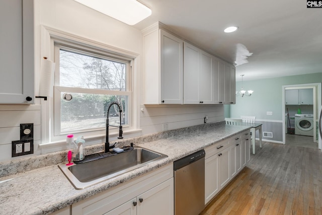 kitchen with dishwasher, washer / dryer, sink, and white cabinets