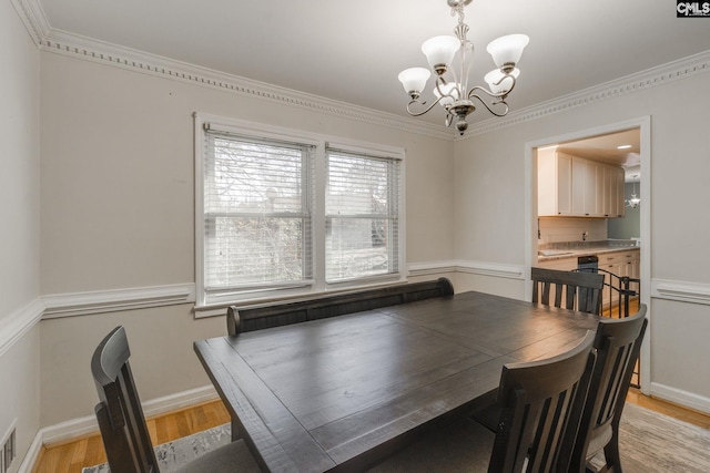 dining room featuring a notable chandelier, light hardwood / wood-style flooring, and ornamental molding