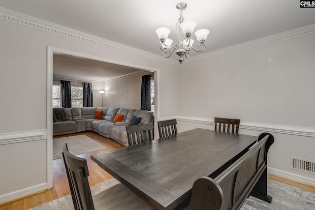 dining area featuring crown molding, light hardwood / wood-style floors, and a notable chandelier