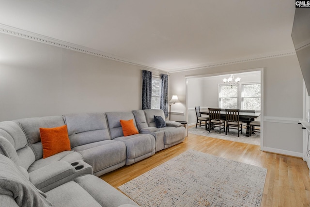 living room with a notable chandelier, light hardwood / wood-style flooring, and ornamental molding