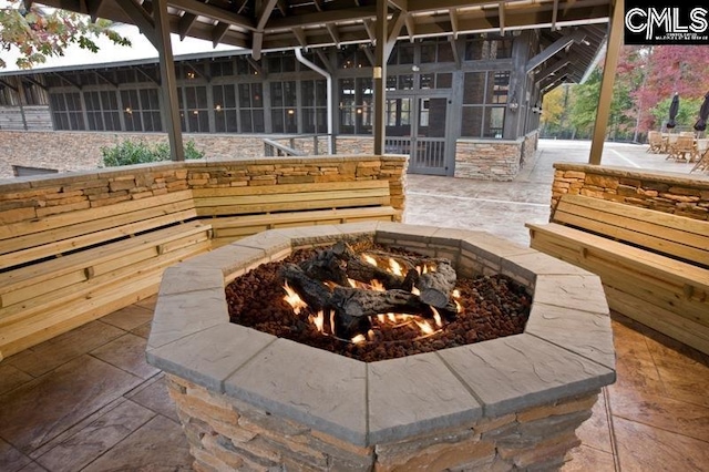 exterior space with a sunroom and an outdoor fire pit