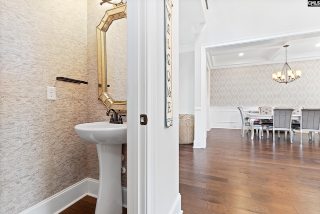 bathroom with a notable chandelier, hardwood / wood-style flooring, and ornamental molding