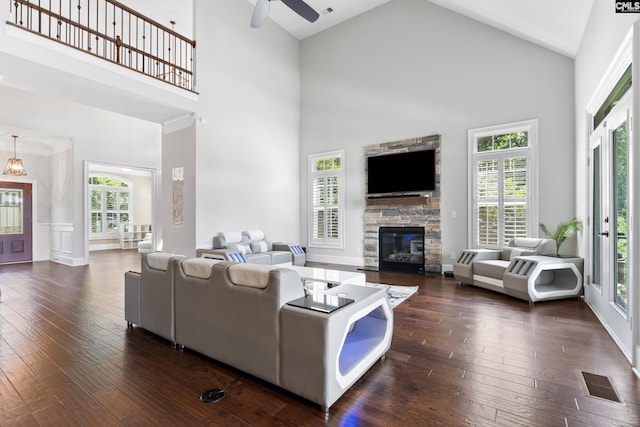 living room featuring ceiling fan, high vaulted ceiling, dark wood-type flooring, and a fireplace