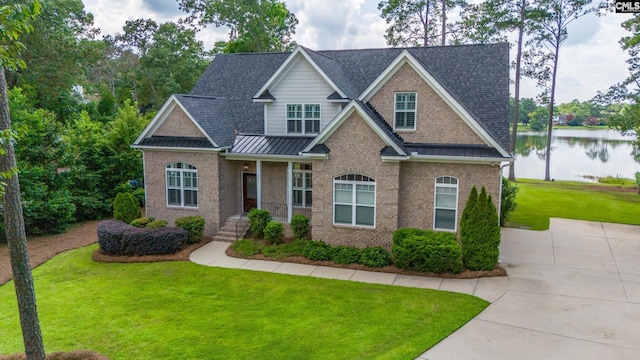 craftsman house with a water view and a front lawn