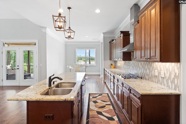 kitchen featuring pendant lighting, sink, a kitchen island with sink, backsplash, and stainless steel gas stovetop