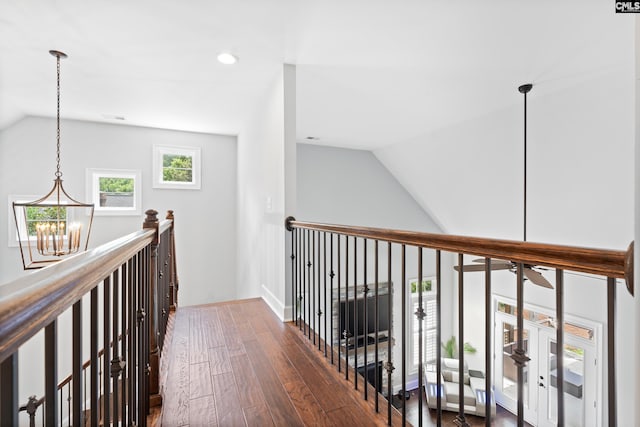 hall with vaulted ceiling, dark wood-type flooring, and an inviting chandelier