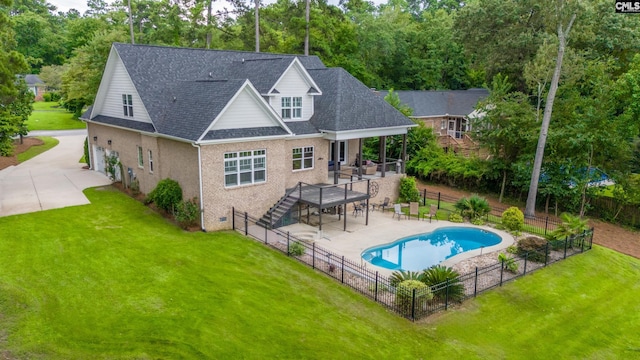 rear view of property with a pool side deck, a patio area, and a lawn