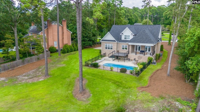 rear view of house featuring a yard, a fenced in pool, and a patio area