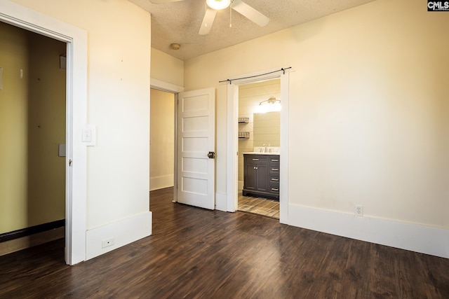 unfurnished bedroom with ensuite bathroom, sink, a textured ceiling, and dark hardwood / wood-style flooring