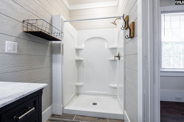 bathroom with vanity, wood-type flooring, a wealth of natural light, and a shower