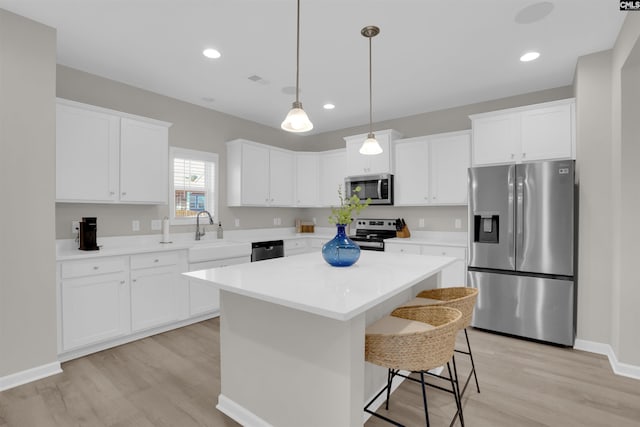 kitchen with a kitchen island, appliances with stainless steel finishes, sink, and white cabinets