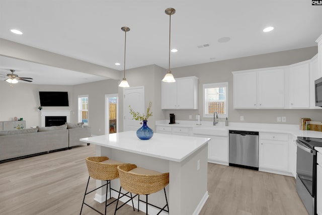 kitchen with stainless steel appliances, sink, a kitchen island, and white cabinets