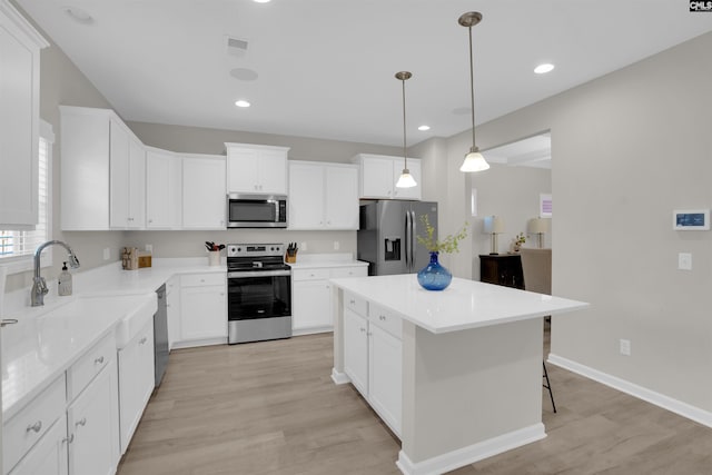 kitchen featuring white cabinetry, pendant lighting, stainless steel appliances, and a kitchen island