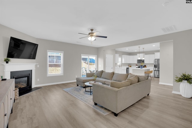 living room with light hardwood / wood-style floors and ceiling fan