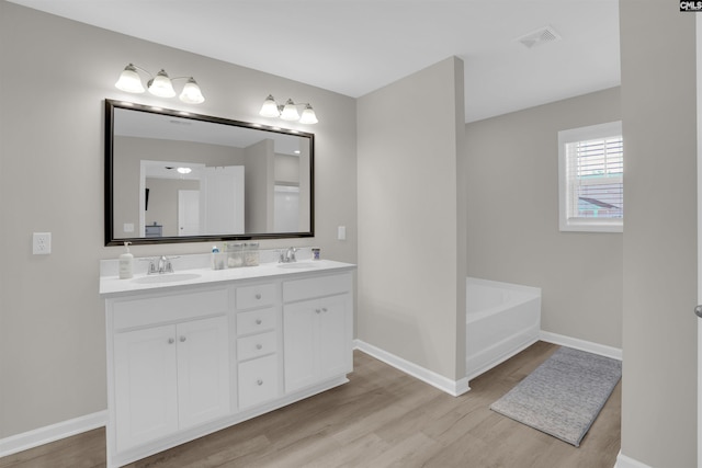 bathroom featuring vanity, a washtub, and hardwood / wood-style flooring