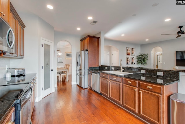 kitchen featuring sink, dark stone countertops, dark hardwood / wood-style floors, ceiling fan, and stainless steel appliances