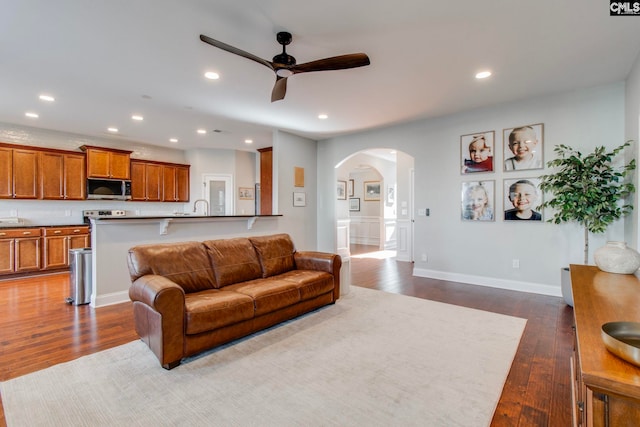 living room with hardwood / wood-style floors, sink, and ceiling fan