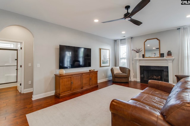 living room with ceiling fan, a high end fireplace, and dark hardwood / wood-style flooring