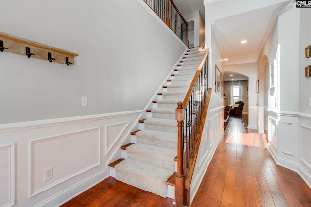 staircase with wood-type flooring and ornamental molding