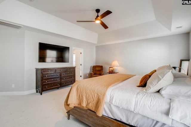 carpeted bedroom with a tray ceiling and ceiling fan