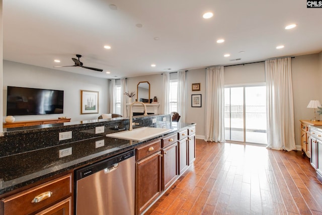 kitchen with sink, stainless steel dishwasher, ceiling fan, dark stone counters, and light hardwood / wood-style floors