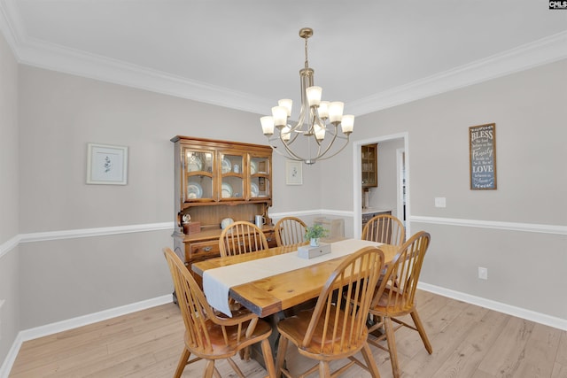 dining space with crown molding, light hardwood / wood-style floors, and a notable chandelier