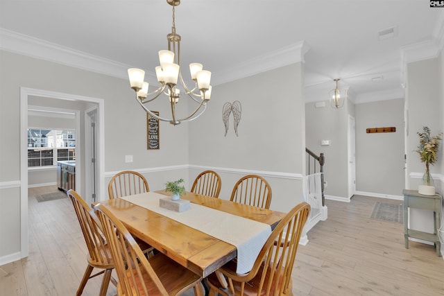 dining space featuring ornamental molding, light hardwood / wood-style floors, and a notable chandelier