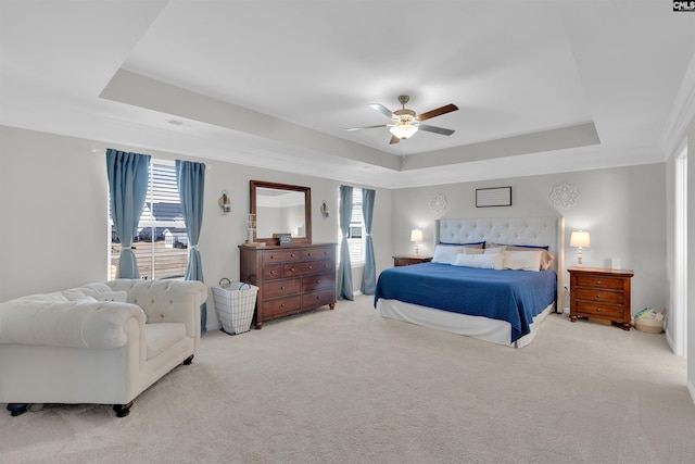 carpeted bedroom with a tray ceiling and ceiling fan