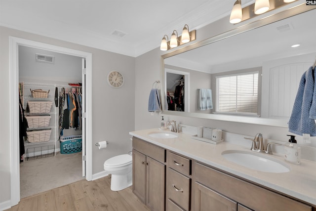 bathroom with crown molding, wood-type flooring, toilet, and vanity