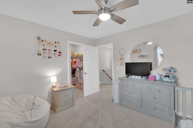 bedroom featuring a walk in closet, light carpet, ceiling fan, and a closet