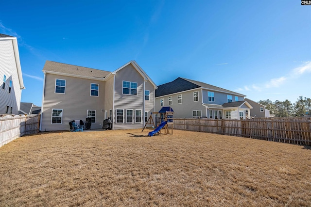 rear view of property with a playground and a yard