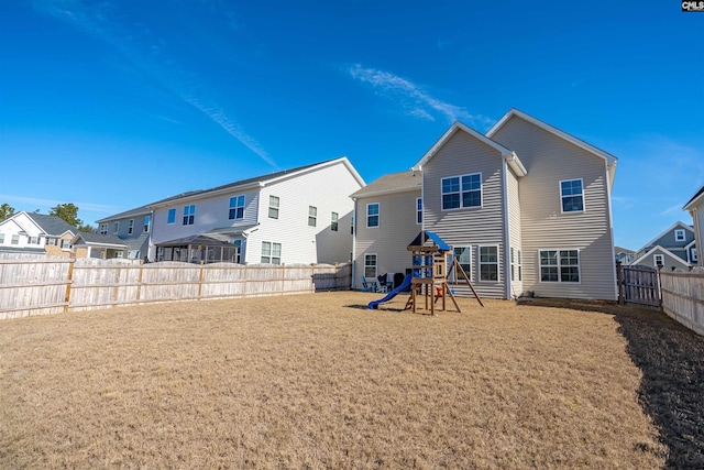 back of house featuring a yard and a playground