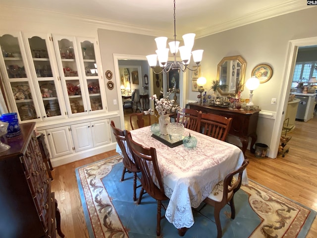 dining space with ornamental molding, a notable chandelier, and light wood-type flooring