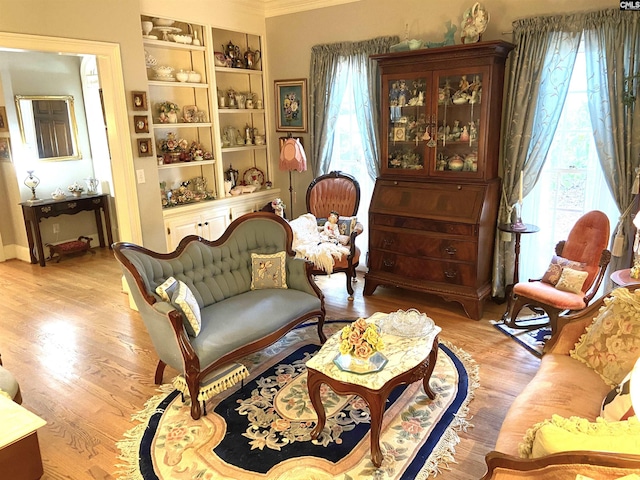 sitting room featuring ornamental molding, built in features, and light hardwood / wood-style flooring