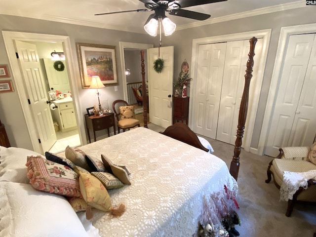 bedroom featuring crown molding, ensuite bath, carpet flooring, two closets, and ceiling fan