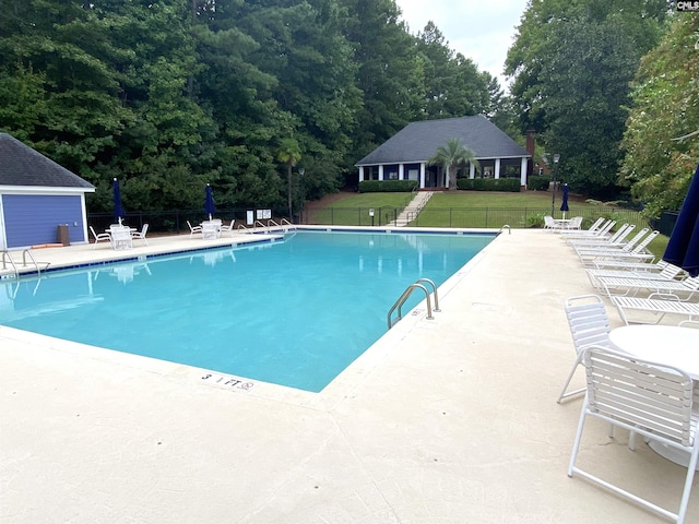 view of swimming pool featuring a patio and a yard