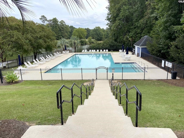 view of swimming pool with a water view, a patio area, and a lawn