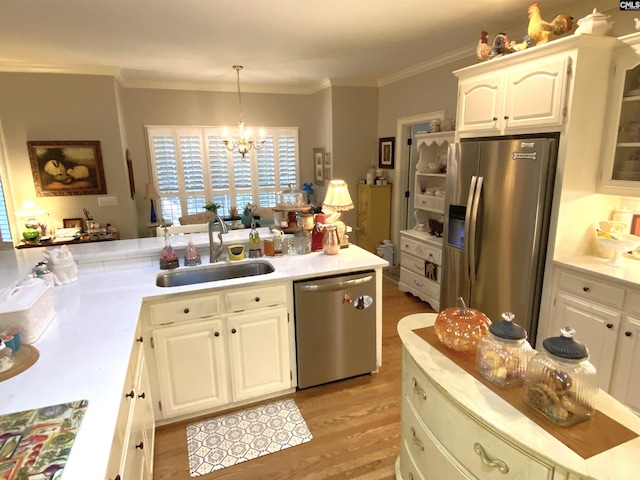 kitchen with decorative light fixtures, white cabinetry, sink, stainless steel appliances, and crown molding