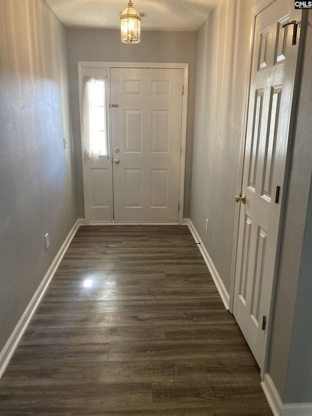 doorway with a textured ceiling and dark hardwood / wood-style flooring